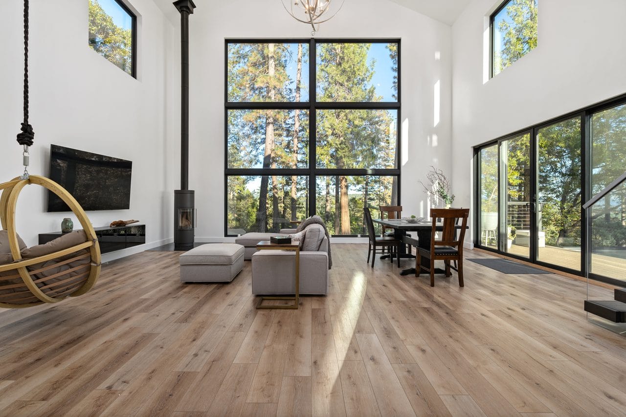 Modern living room with wood stove, hanging chair and full-height black windows