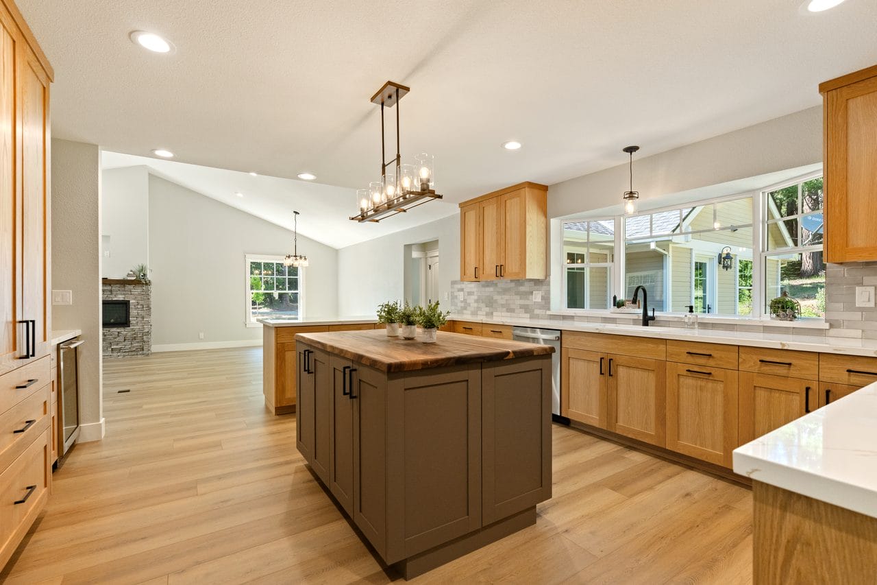 Kitchen with wood island, lantern chandelier and vaulted ceiling over oak floors