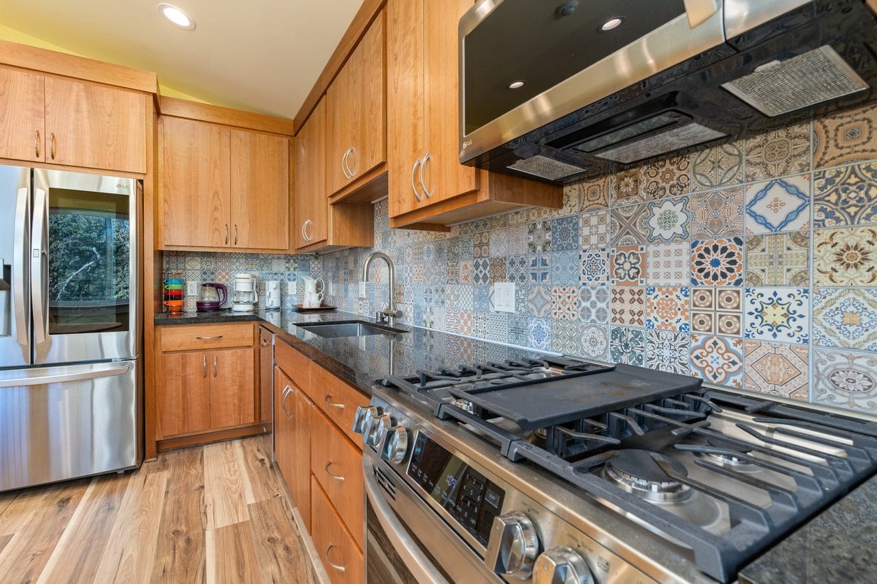 Maple kitchen with gas cooktop and a colourful patchwork tile backsplash