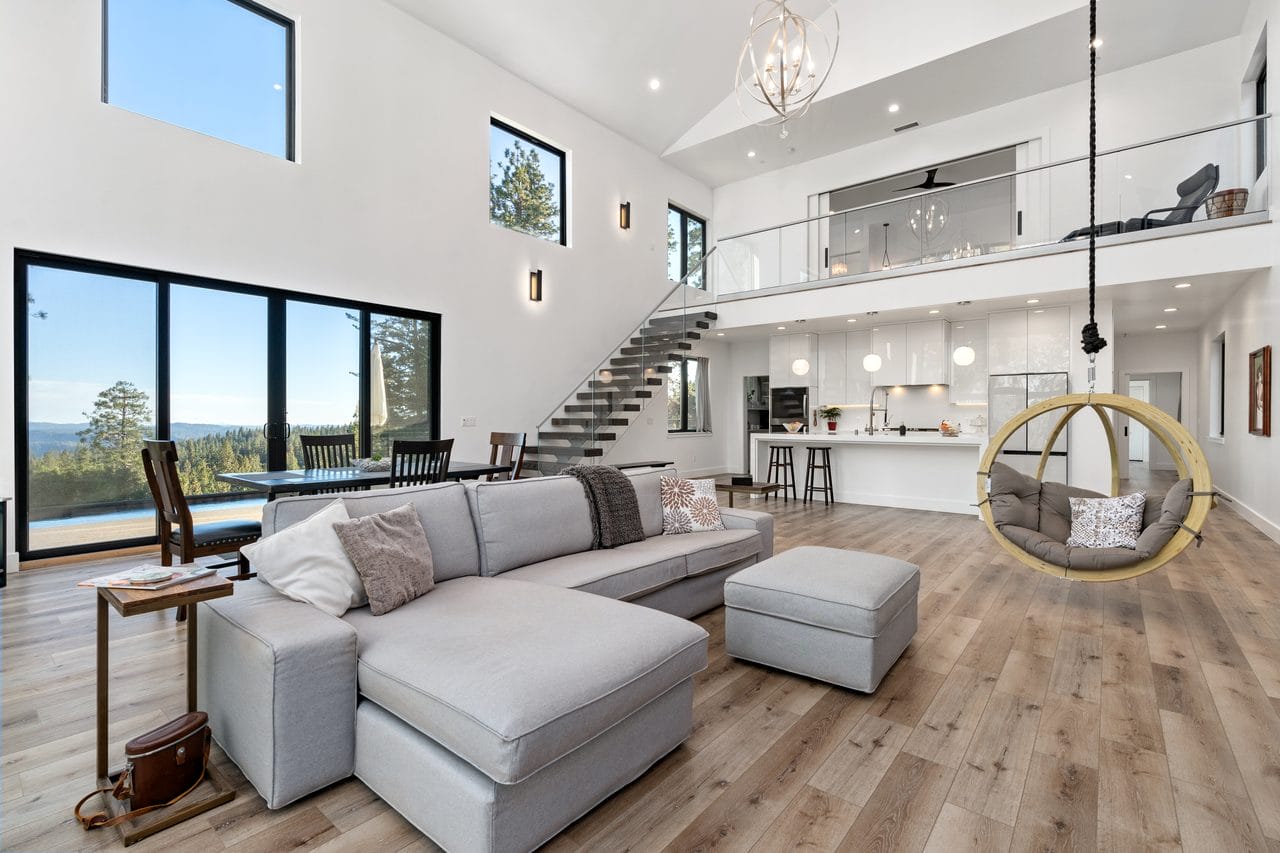 Modern living room with grey sectional, hanging chair and mezzanine above