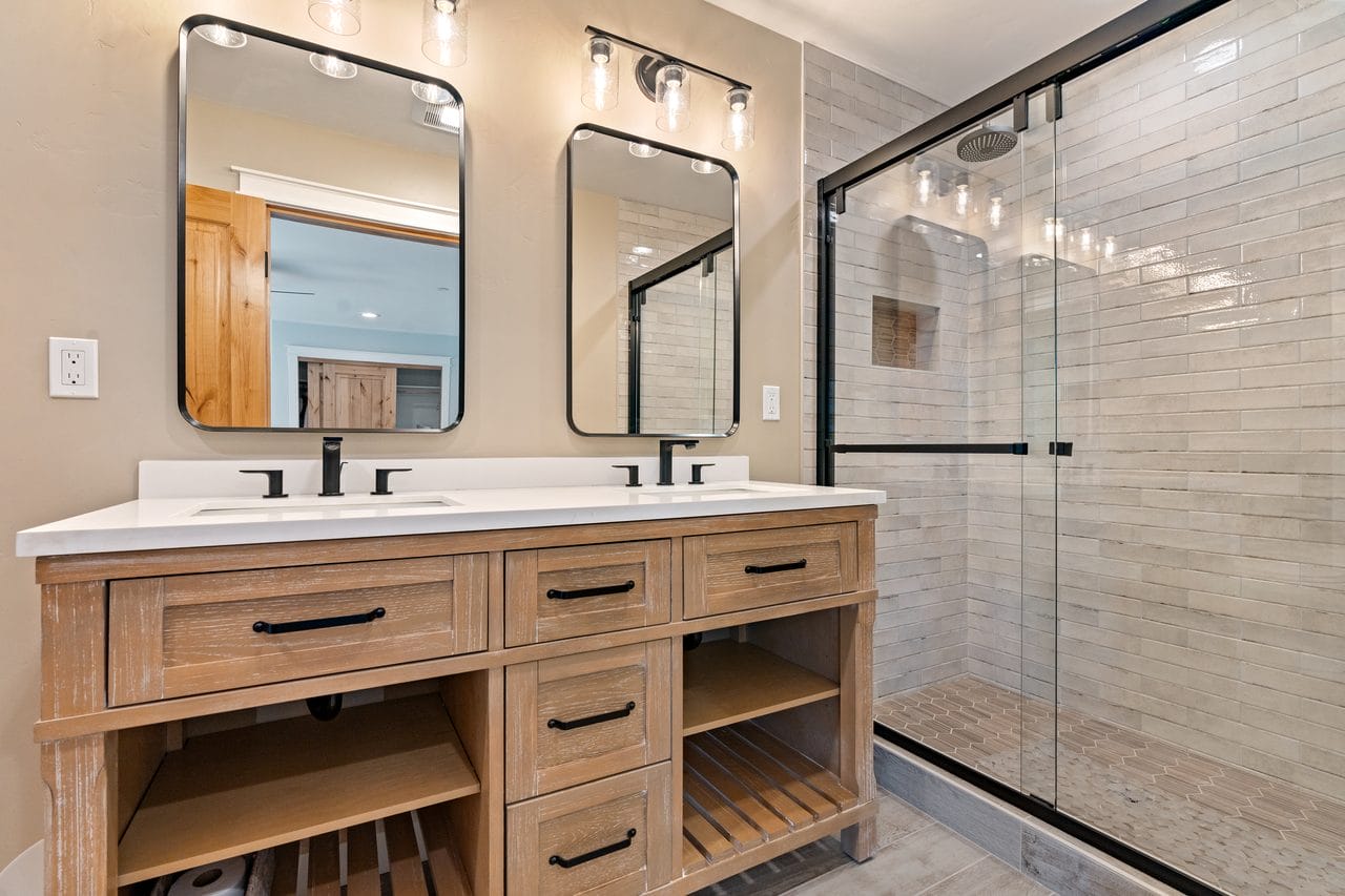 Bathroom with oak double vanity, twin framed mirrors and a glass walk-in shower