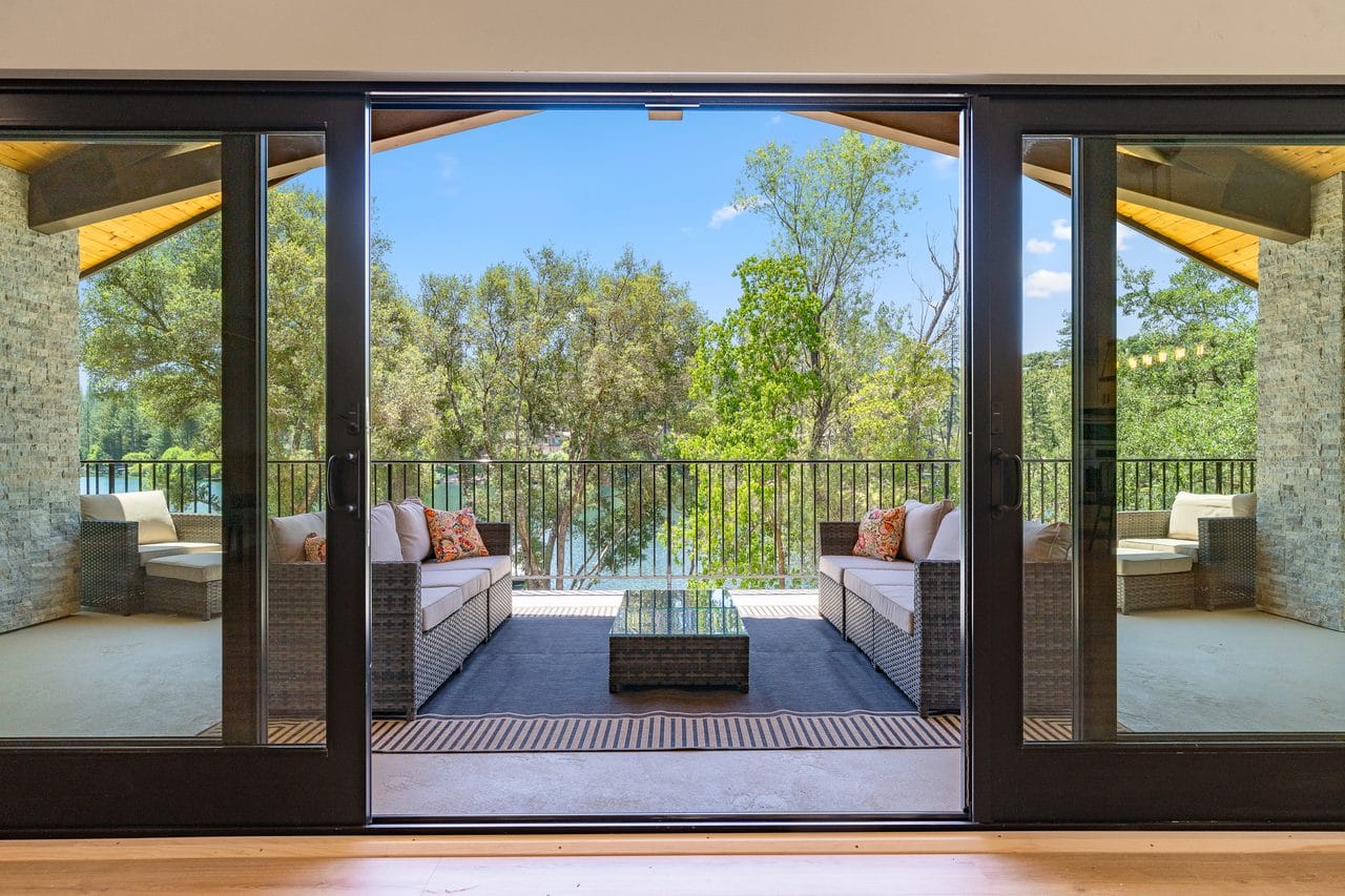 Wide sliding glass doors opening onto a covered deck with treetop views